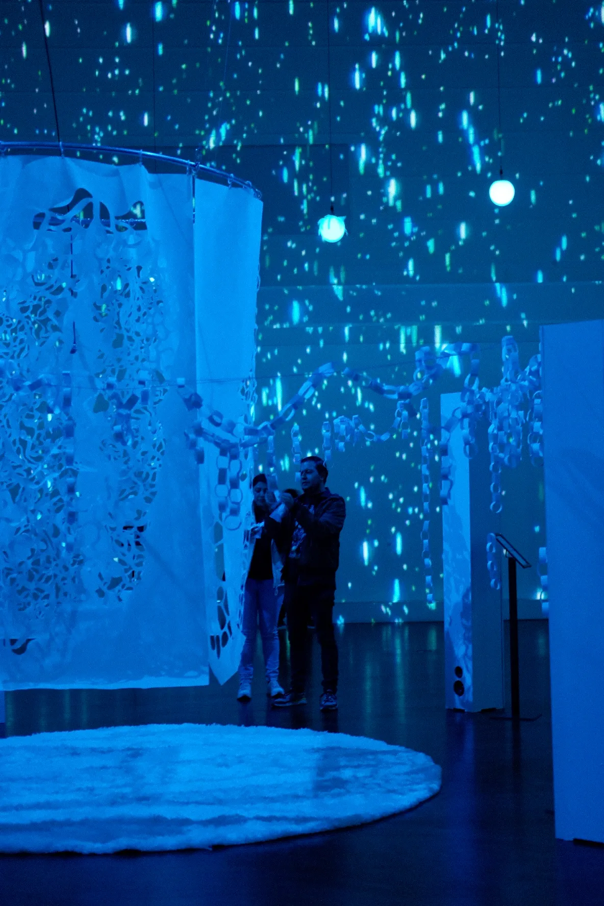 Visitors in the exhibit among projected light and hand-cut paper